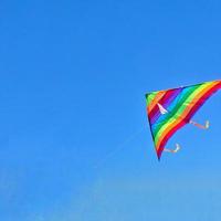 Rainbow kite flying in blue sky with clouds photo