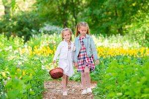 jardín de primavera, flores de primavera, niñas adorables y tulipanes. niños lindos con una canasta en un jardín floreciente en un día cálido foto