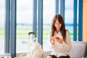 Female passenger in an airport lounge waiting for flight aircraft. Silhouette of woman with cellphone in airport go to landing