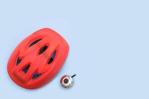 red bicycle helmet and bicycle bell on blue background with copy space