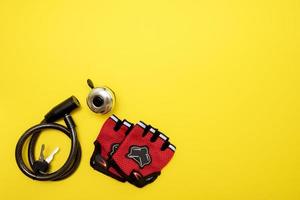 bike lock, bell and gloves on yellow background with copy space photo