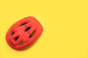 casco de bicicleta rojo sobre fondo amarillo con espacio de copia foto