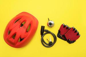 bicycle accessories - helmet, bell, lock with keys, gloves on a yellow background. photo