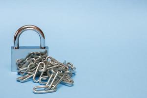 closed padlock with chain on blue background with copy space photo