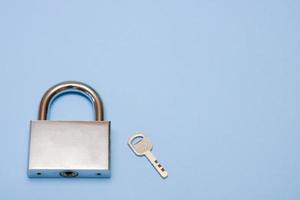 padlock and key on a blue background with copy space, security, reliability photo