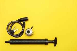 bicycle lock with keys, bell and pump on yellow background with copy space photo