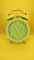despertador verde sobre fondo amarillo. concepto de tiempo copie el espacio foto