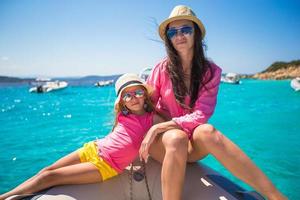 Young mother with her adorable daughter enjoy vacation on a boat photo