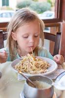 Adorable little girl eating spaghetti in outdoors restaraunt photo
