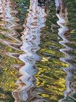 formas onduladas abstractas de reflejos de troncos de árboles en la superficie del lago athalassa, nicosia, chipre. foto