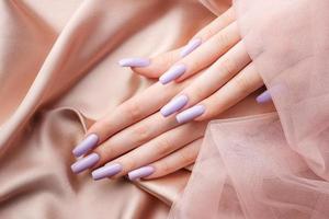manos de niña con una manicura violeta suave. foto