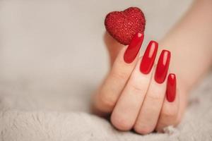 manos de niña con manicura roja y corazón decoratine foto