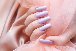 manos de niña con una manicura violeta suave. foto