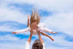 Happy father and cute little daughter have fun during beach vacation photo