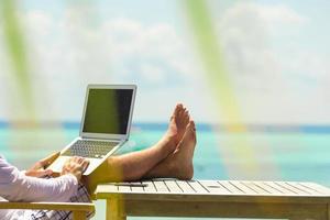 Young man with tablet computer during tropical beach vacation photo