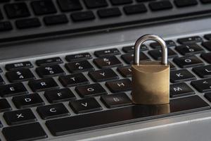 Internet y seguridad informática representada por un candado cerrado sobre un teclado negro foto