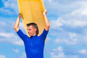 joven feliz surfeando en la costa tropical foto