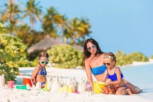 familia haciendo castillos de arena en la playa blanca tropical