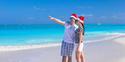 Happy couple wearing Santa hat at caribbean beach photo