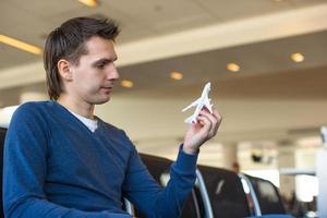 Happy man with small model airplane inside airport photo