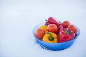 primer plano de un plato hondo con deliciosas verduras, pimientos, berenjenas y tomates en la nieve blanca foto