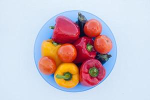 primer plano de un plato hondo con deliciosas verduras, pimientos, berenjenas y tomates en la nieve blanca foto