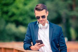 Man is reading text message on mobile phone while walking in the park photo