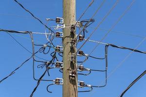 los cables eléctricos se enredan en un poste de madera foto