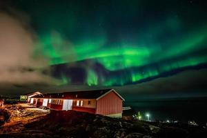 auroras boreales verdes y brillantes ocultas por las nubes sobre casas vivas en el fiordo, ciudad de nuuk, groenlandia foto
