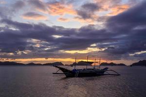 barco de crucero parado en el agua con puesta de sol en el fondo, palawan, filipinas foto