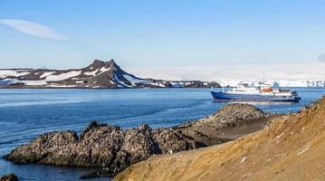 crucero antártico azul en la laguna y colonia de pingüinos gentoo en la costa rocosa de la isla barrientos, antártida foto
