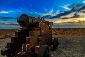 Old Spanish Cannon on the carriage in San Pedro de La Roca fort walls, with Caribbean sea sunset view, Santiago De Cuba, Cuba photo