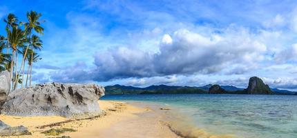 Tropical beach panorama with blue sky, clouds, rocks and palm trees, Palawan, Philippines photo