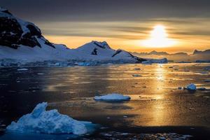 icebergs azules, montañas y sol polar reflejados en la laguna marina en el estrecho de Lemaire, viaje en crucero por la Antártida
