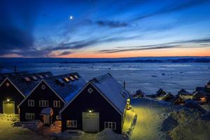 Village at the fjord covered in snow, sunset view with moon, Nuuk city, Greenland