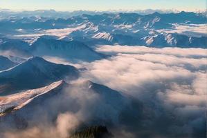 aerial landscape photo shot of a mountain from above, mist and snow