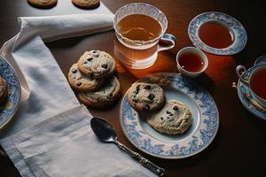 fotografía de un plato de galletas y un vaso de té sobre una mesa con un paño y una servilleta encima foto