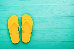 Yellow flip flops on blue wooden background. Summer holidays. Top view. Mock up. Copy space photo