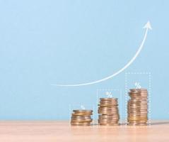 A stack of metallic coins and a graph on a blue background. Income growth in business, photo