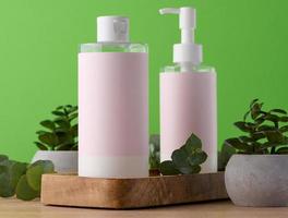 Two bottles for cosmetics with a pink paper label on a green background. Bottle for tonic, gel photo