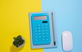 Bloc de notas azul, calculadora y lápiz de madera sobre un fondo azul. foto