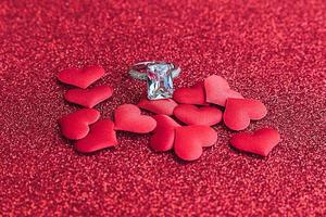 Will you marry me. Wedding ring and many red hearts on red glitter background. Engagement marriage proposal wedding concept. St. Valentine's Day postcard. Banner on valentines day. photo