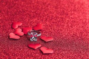 Will you marry me. Wedding ring and many red hearts on red glitter background. Engagement marriage proposal wedding concept. St. Valentine's Day postcard. Banner on valentines day. photo