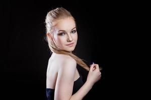 Beauty fashion model girl with long healthy smooth straight hair ponytail hairstyle on black background. Smiling pretty woman looking camera. Perfect Fresh Skin Portrait. Youth and Skin Care Concept. photo