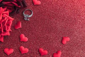 Te casarías conmigo. anillo de bodas rosas escarlatas rojas y muchos corazones rojos sobre fondo de brillo rojo. concepto de boda de propuesta de matrimonio de compromiso. S t. postal del día de san valentín. pancarta en el día de san valentín. foto