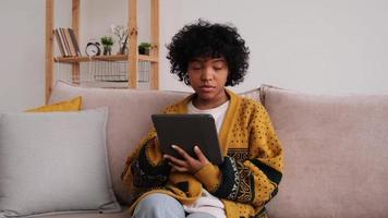 African american girl holding digital tablet touch screen typing scroll page at home. Woman with mobile tech device surfing internet using social media apps playing game. Study work shopping online. photo