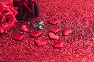 Will you marry me. Wedding ring red scarlet roses and many red hearts on red glitter background. Engagement marriage proposal wedding concept. St. Valentine's Day postcard. Banner on valentines day. photo