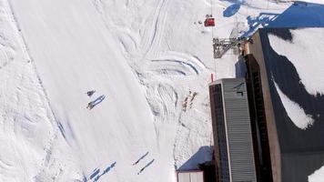 turista de vista aérea ascendente com instrutores aprende a praticar snowboard na encosta por elevador de teleférico video