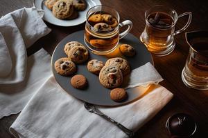 photography of a plate of cookies and a glass of tea on a table with a cloth and a napkin on it photo