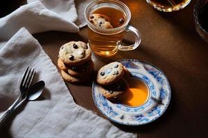 photography of a plate of cookies and a glass of tea on a table with a cloth and a napkin on it photo